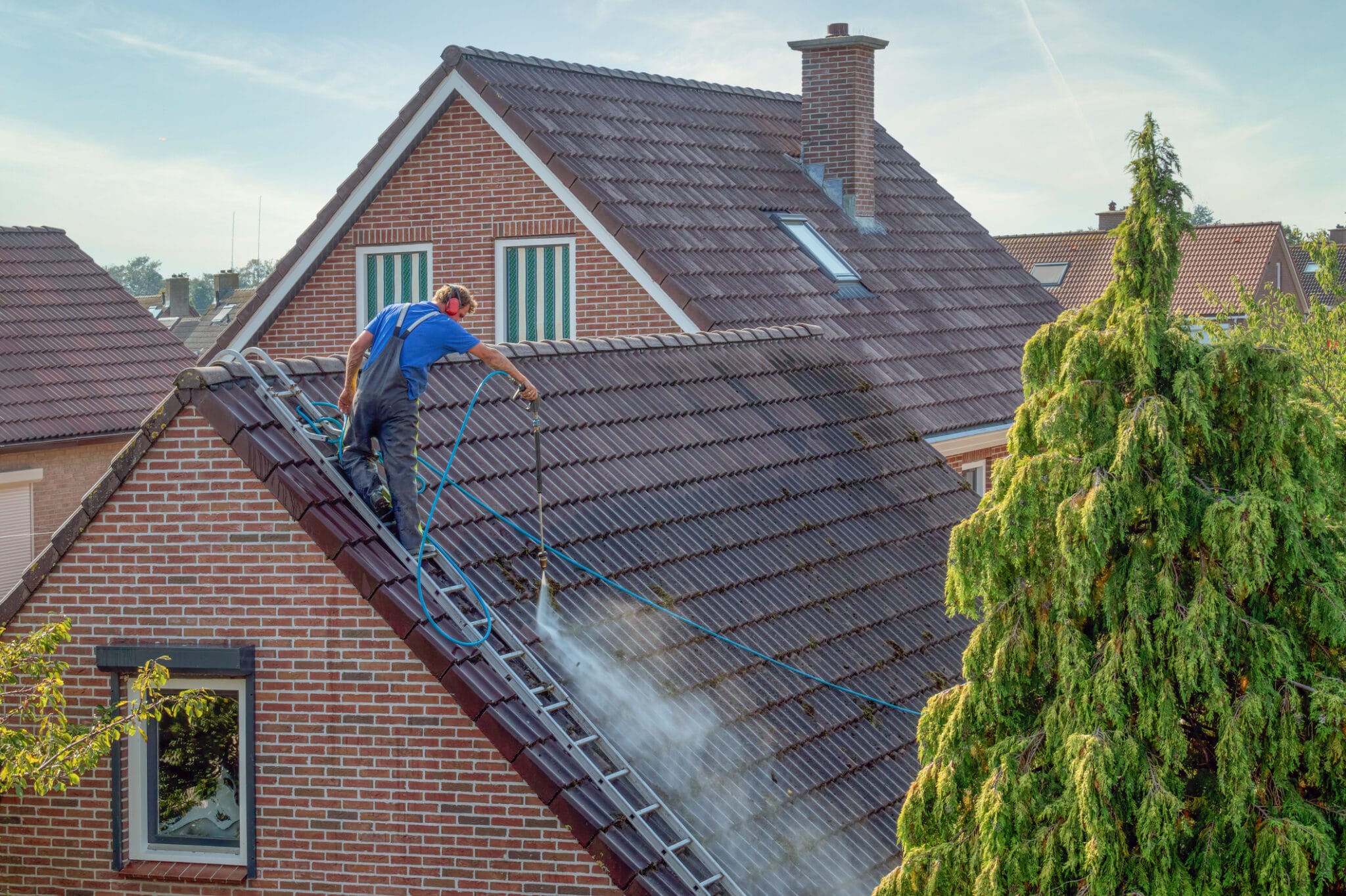 Cleaner with pressure washer at roof house cleaning roof tiles